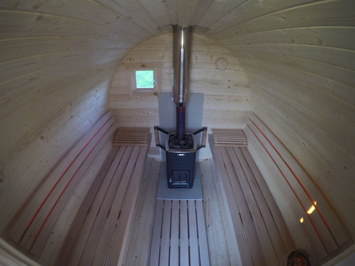 Fasssauna Innenraum mit Holzbänken und Ofen